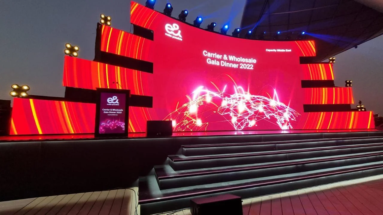 Red illuminated gala dinner stage with large display screens