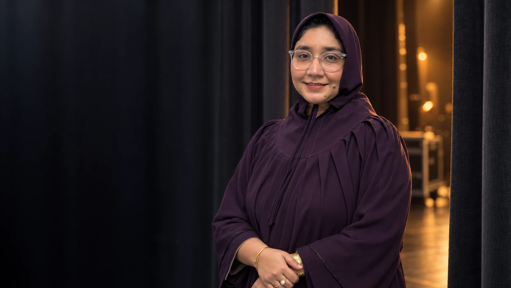 Editorial portrait of Zainab Murtaza in her plum Rida against warm backstage lighting
